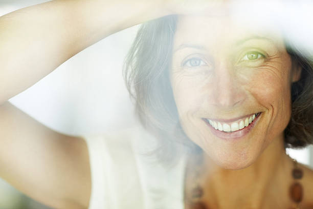 istock Cheerful mature woman looking through a window 183415479