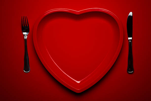 Heart shaped plastic plate on red background stock photo
