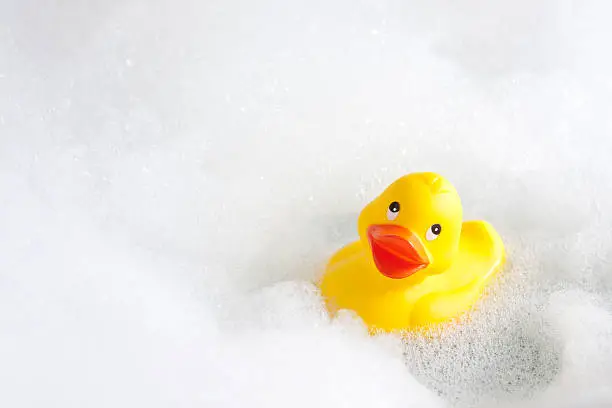 A cheerful yellow rubber duck in a bathtub full of soapy bubbles.See related images:
