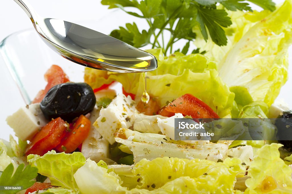 El vertido aceite de oliva en la ensalada - Foto de stock de Aceite para cocinar libre de derechos