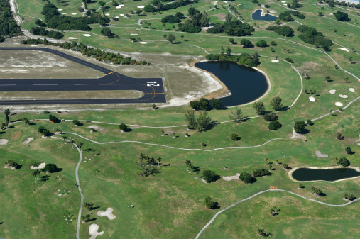 Aerial view of a luxury golf community with a general aviation airport adjacent to it.