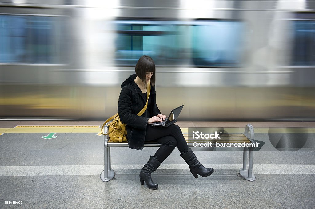 Giovane donna con un computer alla stazione della metropolitana - Foto stock royalty-free di Computer portatile