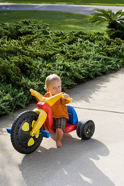 istock Little boy riding tricycle on driveway 183418966