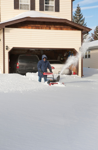 a man uses his snowblower to dig his way out of the snow after a blizzard clobbered the area the night before. Suburbs of Chicago