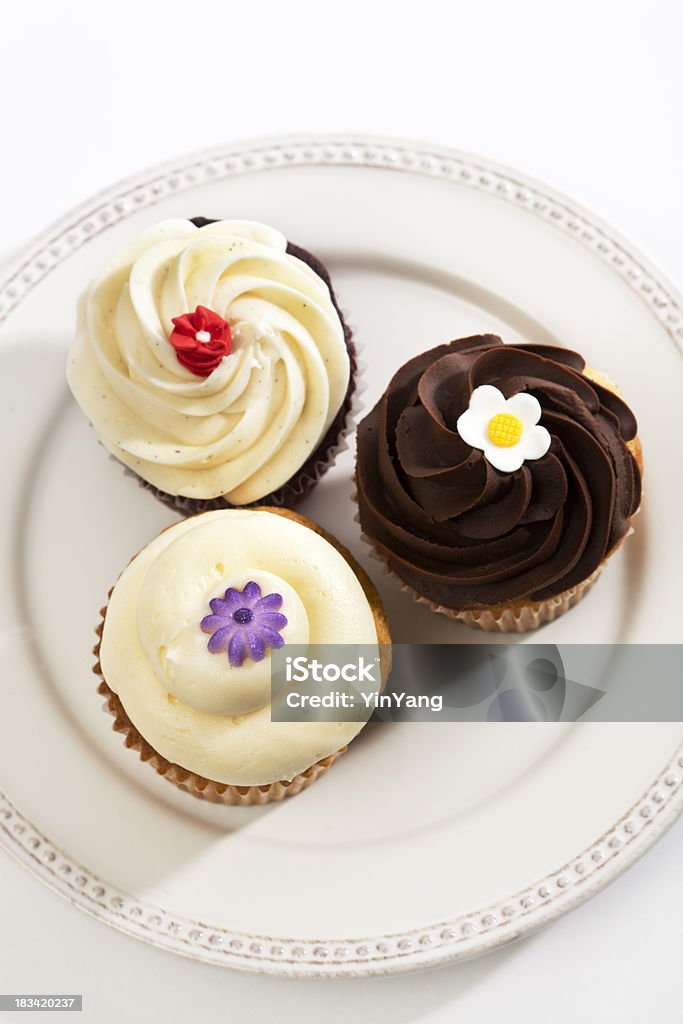 Tres elegantes esmerilado, decoradas Gourmet Sweet Cupcakes sobre placa blanca - Foto de stock de Magdalena con glaseado libre de derechos