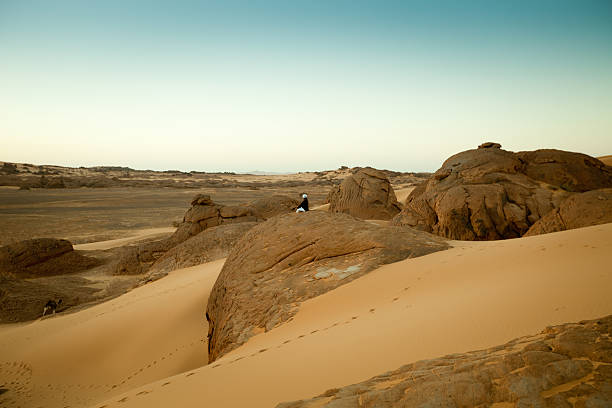 Meditating on a rock in Libyan Sahara desert at dusk