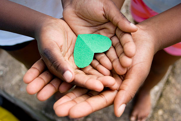 love; beautiful hands of children and precious moments together love; beautiful hands of children holding green heart shape two heads are better than one stock pictures, royalty-free photos & images