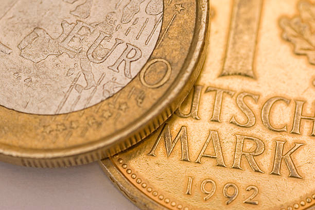 German Mark Replacement Studio shot of a one euro coin and a gold plated German Mark coin as a metaphor to replace the German mark by the euro. scuff marks photos stock pictures, royalty-free photos & images