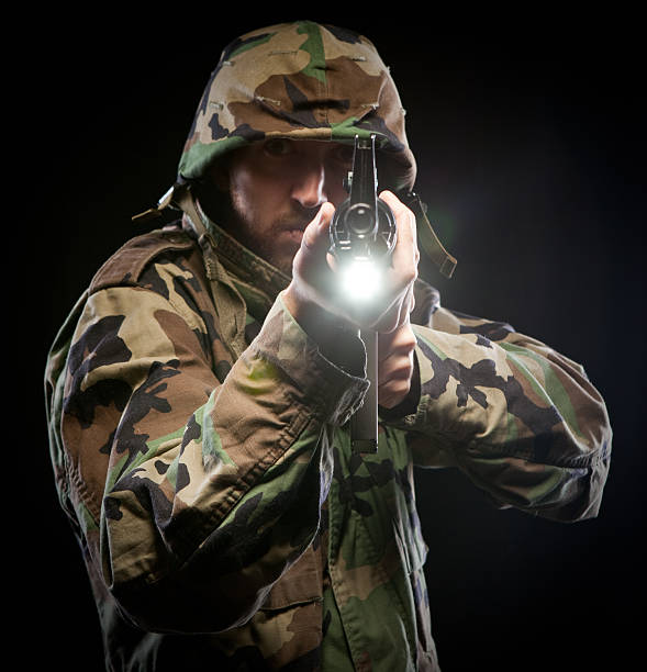 Dead eye soldier aiming weapon M16 at camera US Army man with m16 in the heat of battle.  He is ready for his call of duty and is in action! Green vietnam era camouflage with helmet.  On black background special forces vietnam stock pictures, royalty-free photos & images