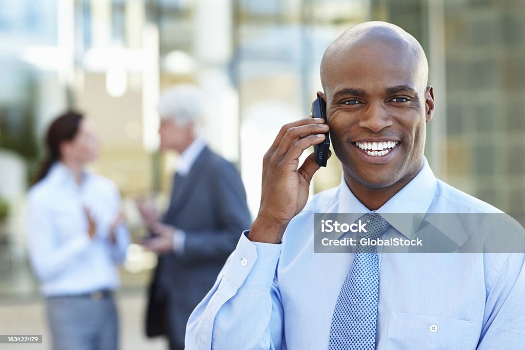 Empresário sorridente, enquanto na chamada telefónica - Royalty-free A usar um telefone Foto de stock