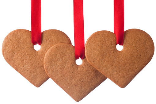 Gingerbread cookies hanging in red ribbon. Isolated on pure white.