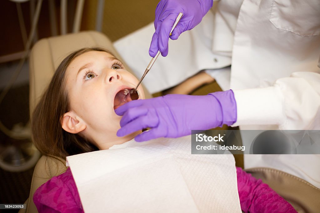 Młoda dziewczyna pierwsze zęby zbadane przez dentystę w gabinecie stomatologicznym - Zbiór zdjęć royalty-free (Dzieciństwo)
