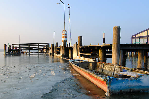 Jetty with boat on frozen lake in evening light