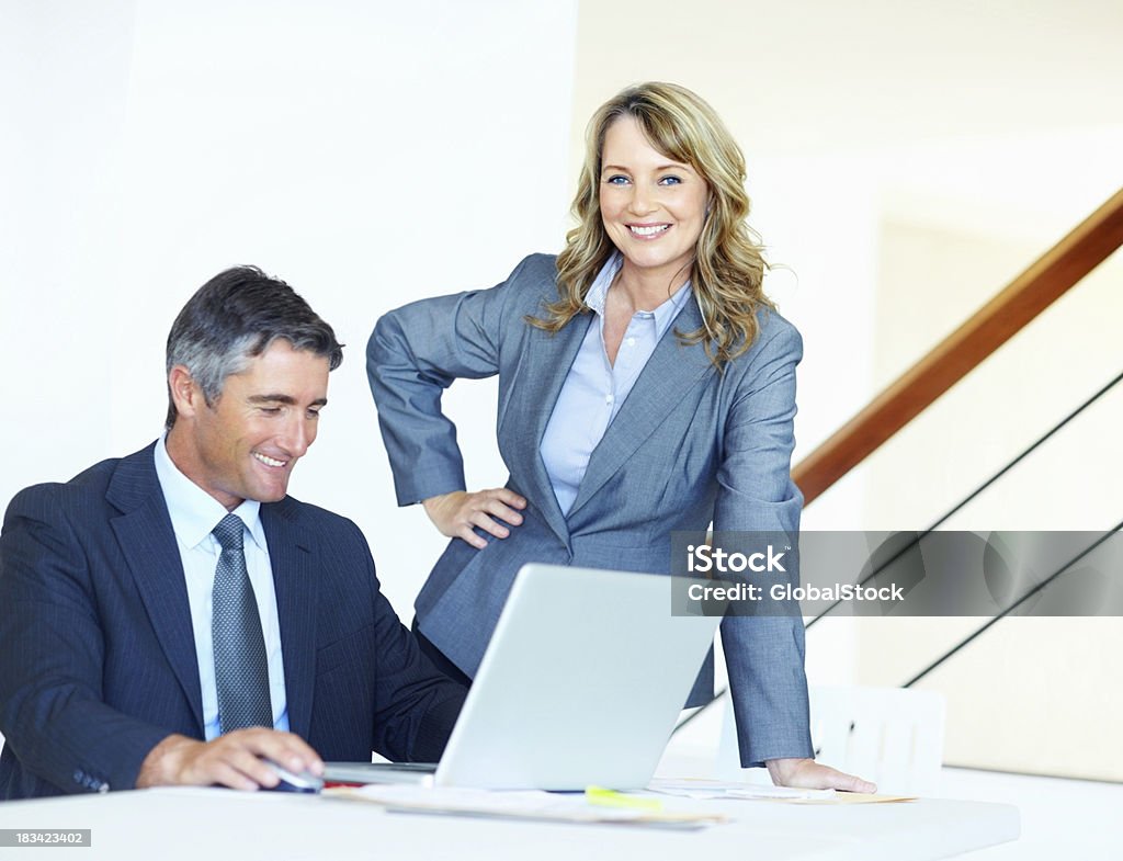 Mujer de negocio feliz con el colega trabajando en la computadora portátil - Foto de stock de 40-49 años libre de derechos