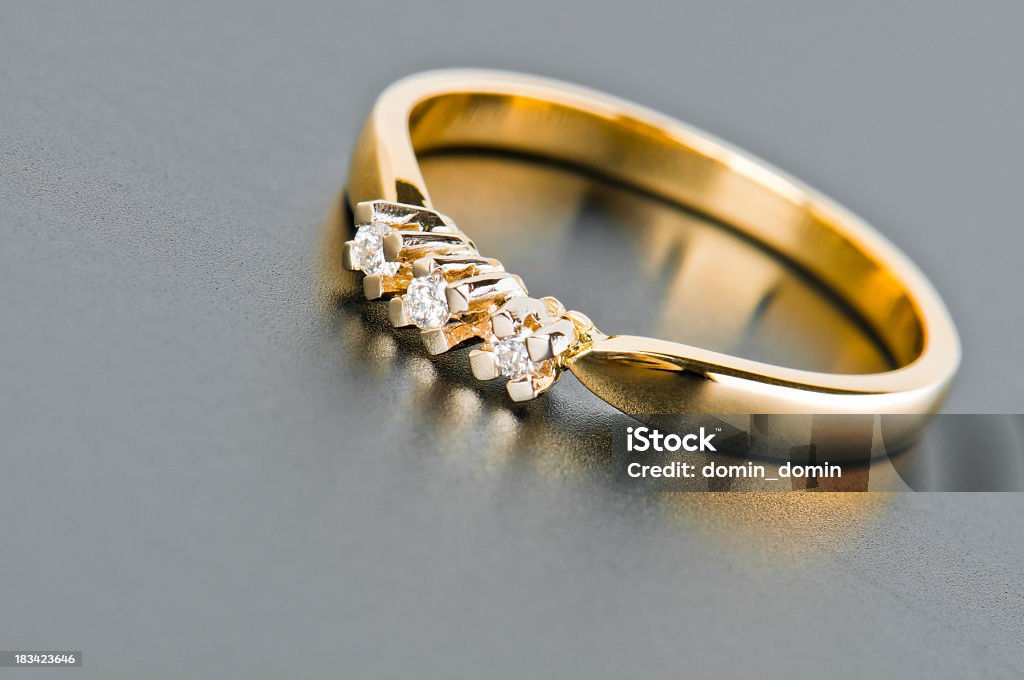Gros plan d'un anneau d'or avec diamants, contre gris uni - Photo de Or - Métal libre de droits