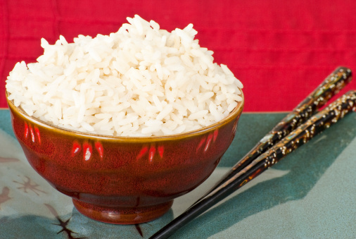 A red bowl with white rice sitting on a blue plate with chopsticks on  a red placemat.Similar Images: