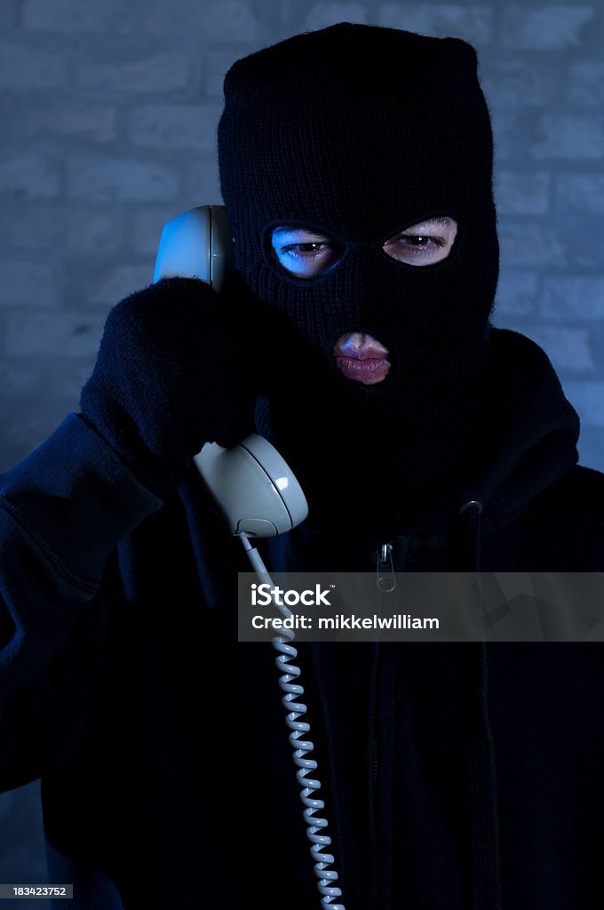 Mala guy con máscara está en el teléfono - Foto de stock de Criminal libre de derechos