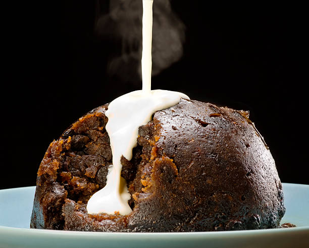 Steamed Christmas Pudding With White Sauce Dark Background  christmas pudding stock pictures, royalty-free photos & images