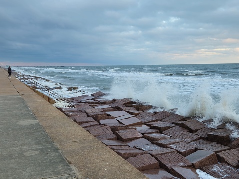 Ocean Waves Splash Against Galveston Seawall Person Silhouette In Background