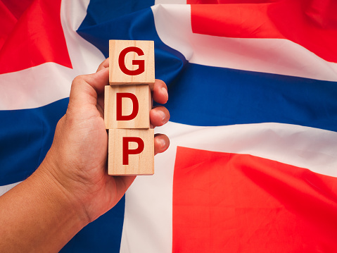 Gross Domestic Product (GDP) of Norway. Close-up of hand-holding wooden cubes with the letters GDP against the Norway flag background. Top view. Flat lay. Business and economy concept