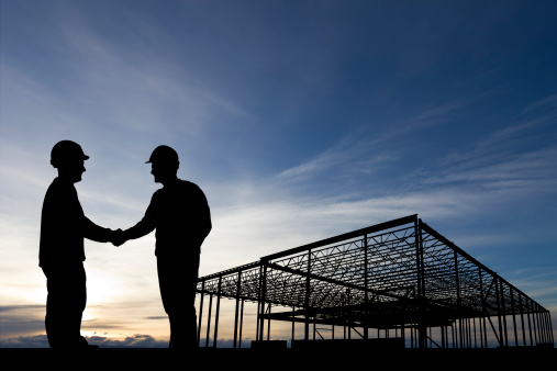 Royalty free image from the construction industry of two construction workers shaking hands at a construction site.