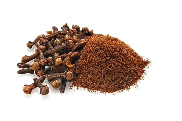 Grouping of whole dried cloves and ground cloves.  Shot on white background with natural reflections.Shot with Nikon D3x and shift lens.