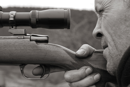 Deer hunter takes aim through his scope.