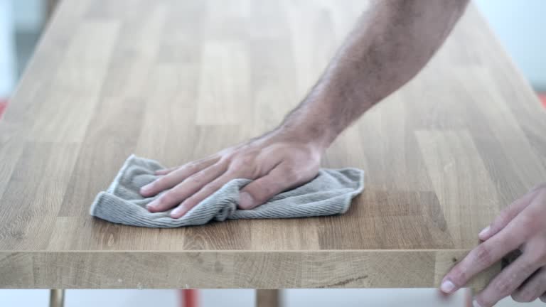 Efficient Cleaning: Man Wiping Wooden Table with Cloth