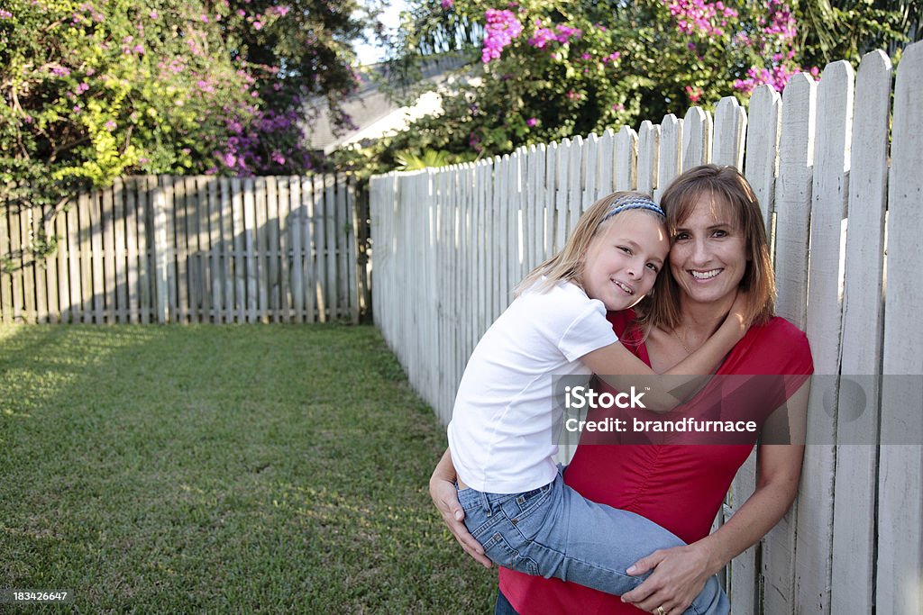 Daughter and mom in backyard Daughter and mom embrace against a fence in the backyard. 30-39 Years Stock Photo