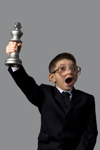Clever little boy lifting chess championship trophy