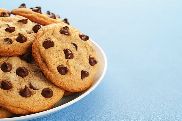 Big plate of freshly baked chocolate chip cookies on blue with plenty of text space.