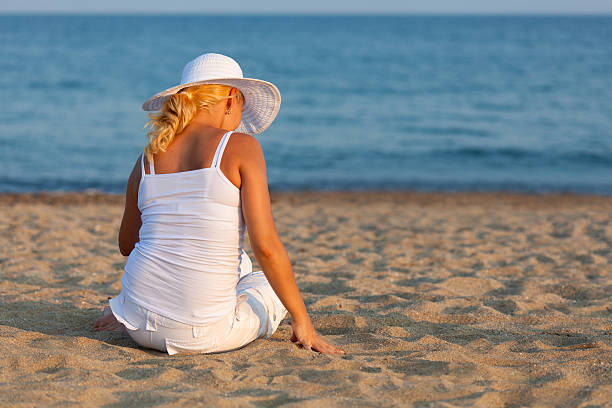 istock Woman in white sitting on sandy beach and relaxing 183428451