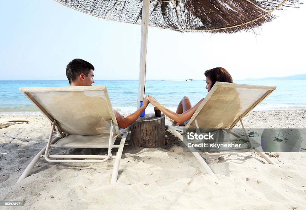 Couple est assis sur la méridienne et profitez - Photo de Plage libre de droits