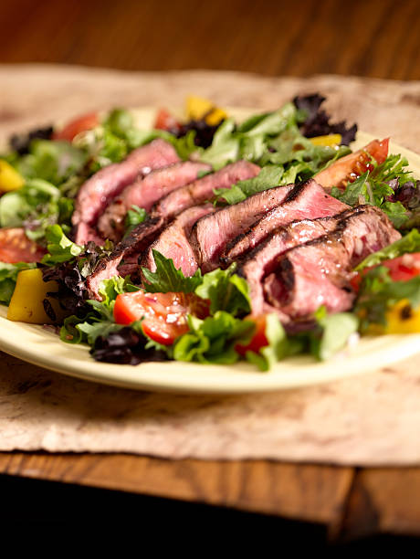 Steak Salad "Beef steak meat with lettuce, tomatoes, peppers and radicchio plated on rustic wood surface." steak salad stock pictures, royalty-free photos & images