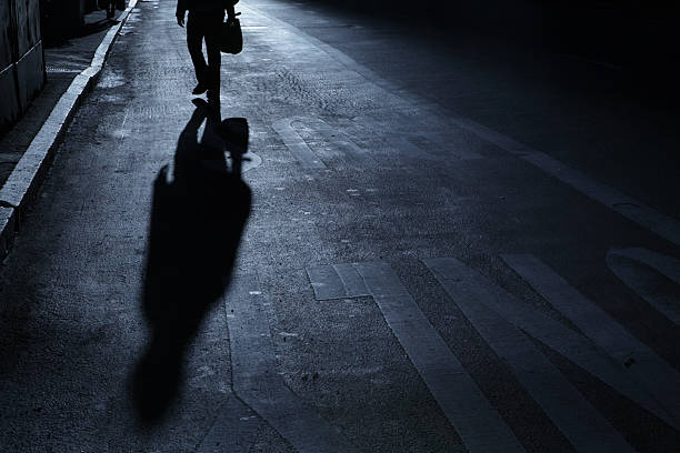 istock Lone man walks up street night shadows 183431169