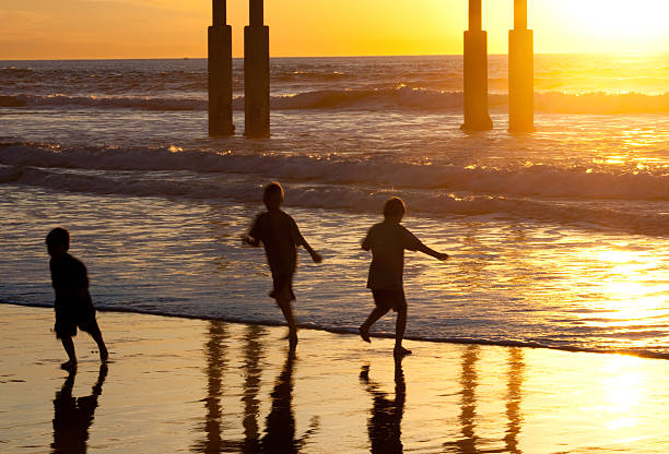 Three children playing on the beach. Long exposure and motion blur.