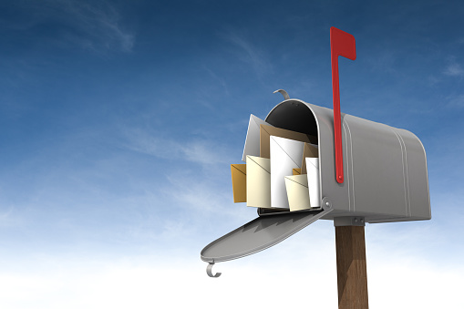 Open red letter box with envelopes near white brick wall. Space for text