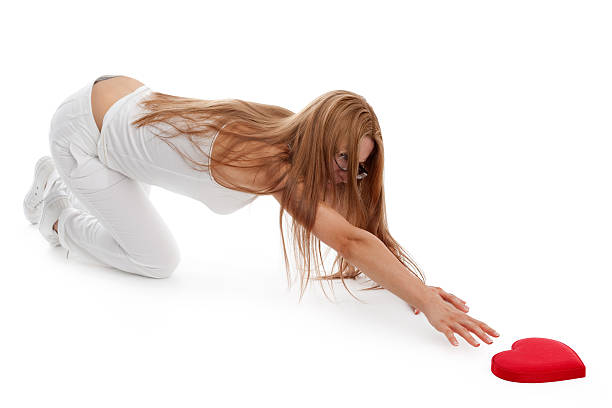 Young woman was reaching ahead on floor to catching the heart with forced expression.