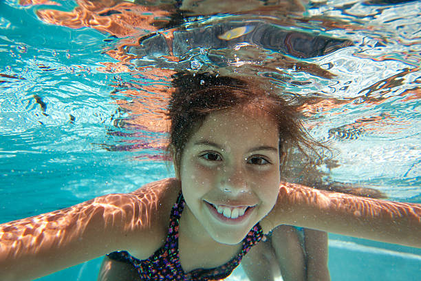Young girl smiling underwater in a swimming pool