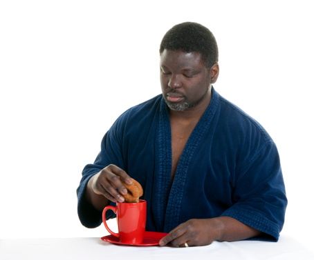 African American man dipping his doughnut into his coffee.