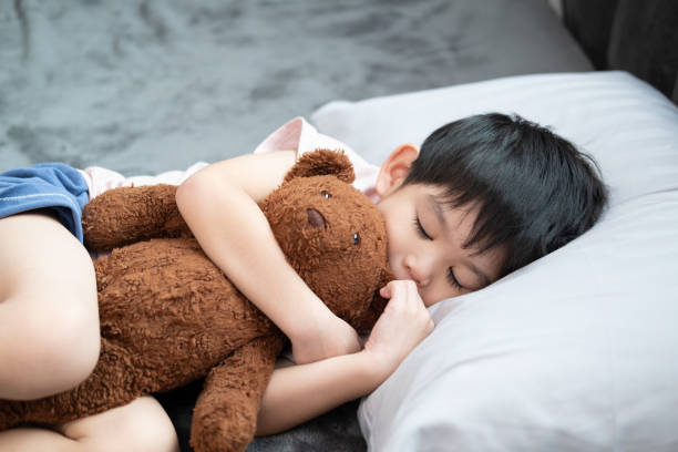 istock A boy is sleeping and hugging a teddy bear in bed. 1834327091