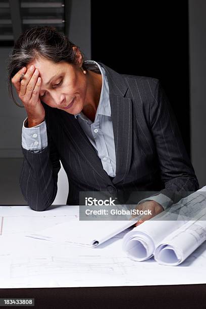 Cansado Mujer Madura Arquitecto Trabajando En Blueprints Foto de stock y más banco de imágenes de Arquitecto