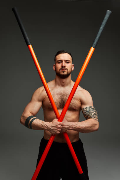 athlete men with stick training karate using sports tool in studio on gray lights background
