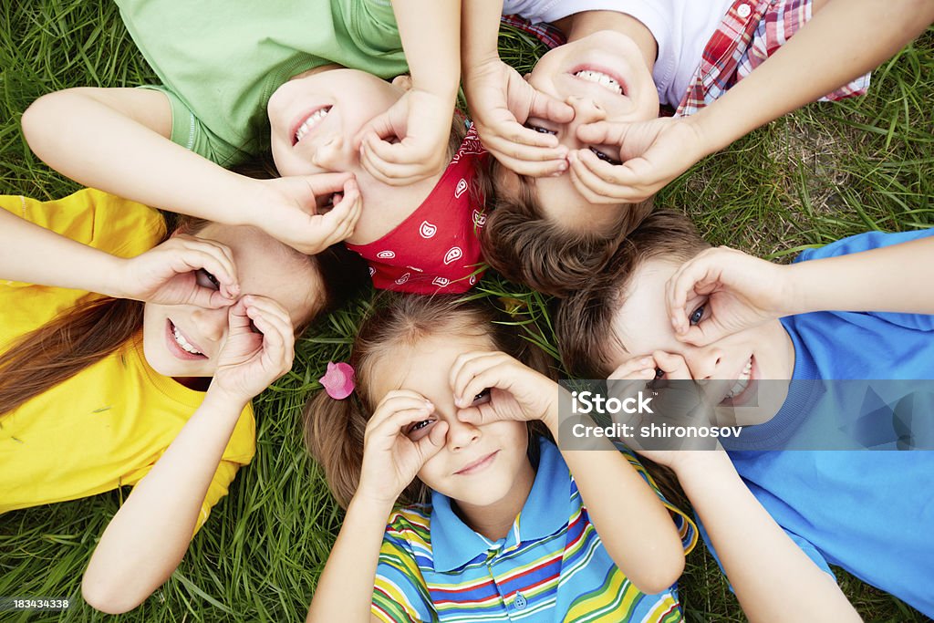 Children resting Group of cute children lying on grass Child Stock Photo