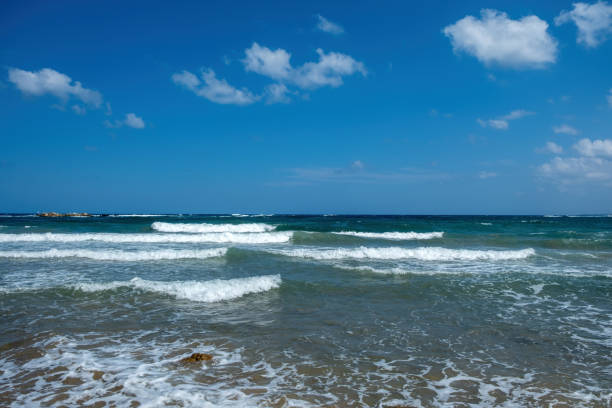 Greece, ripple dark sea water, splashing white foam, blue sky with few cloud background, copy space. Summer vacation destination. Ad template