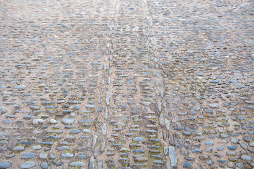 Stone and cement paved footpath background texture, empty cobblestone pathway. Grey paving sidewalk for backdrop. Above view, copy space.