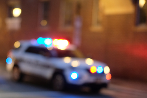 An out-of-focus police SUV sits under street lights.