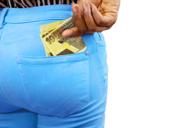 istock Black lady putting few Zimbabwean dollar notes into her back pocket. Removing money from pocket, hold money 1834368351