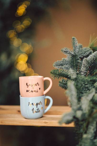 istock Rustic wooden table with two ceramic coffee cups sitting in front of a Christmas tree 1834452132
