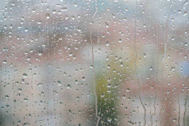 raindrops on windowpane over blurred city view.